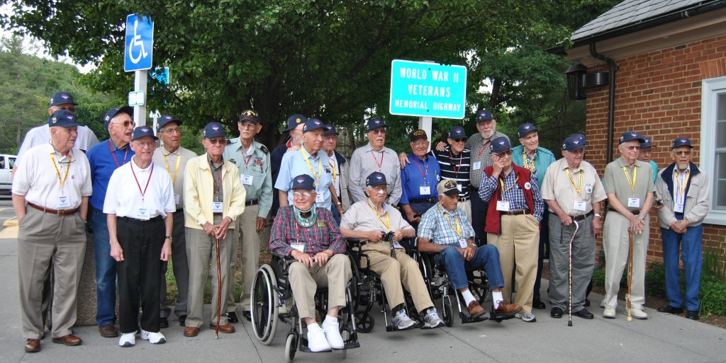 Jessie is standing under the left corner of the sign that reads WW II Veterans Memorial Highway. 