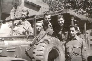 Fletcher at the wheel, Sgt Hanna behind him, McKay smiling, Wilbur standing